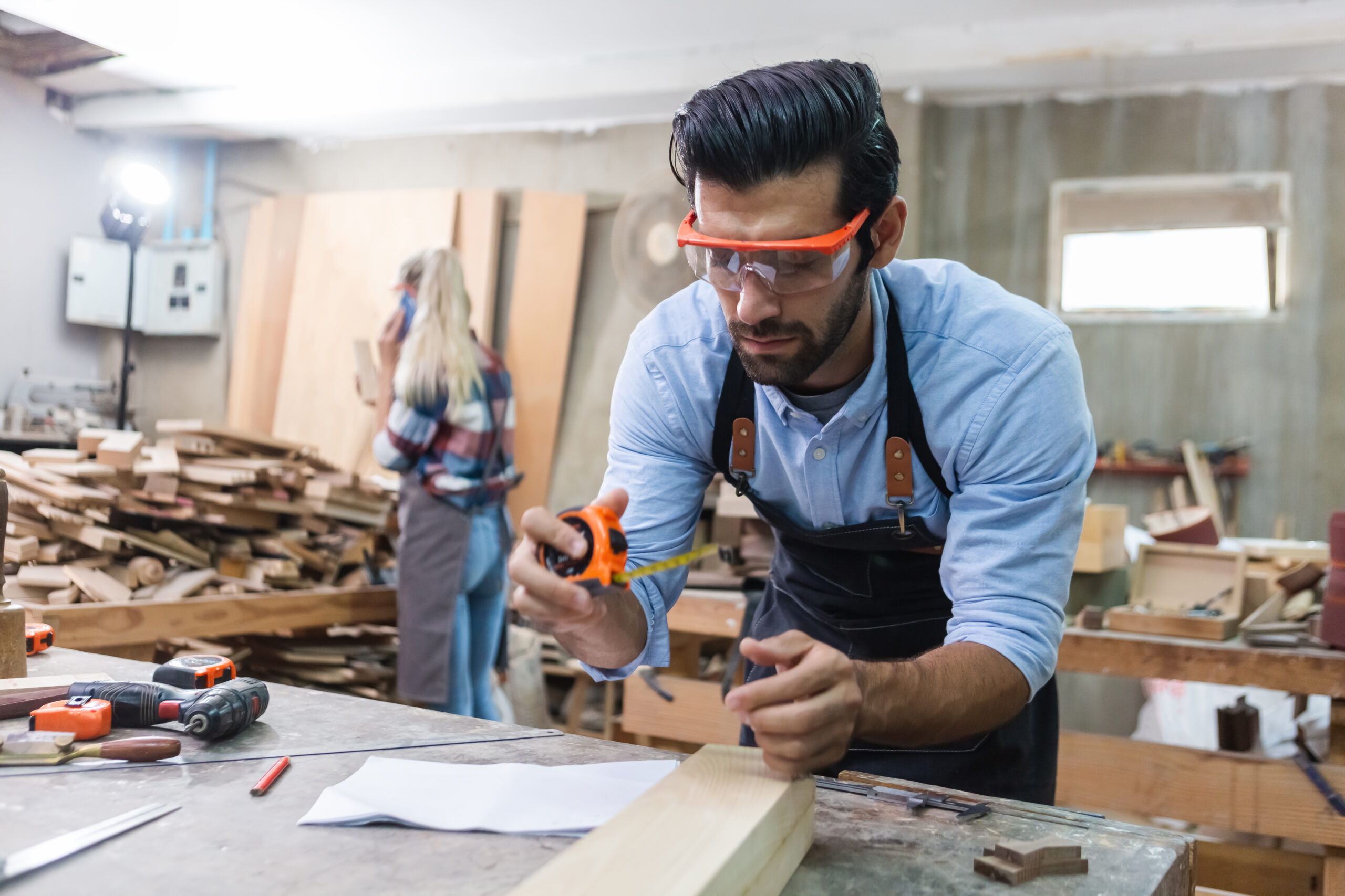 young carpenter caucasian man using measuring tape looking wood